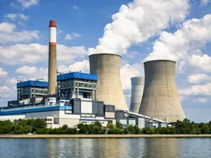 A vast power generation facility situated beside a serene body of water, with towering cooling structures and industrial machinery generating essential energy to meet growing demands.