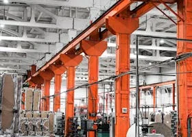 Spacious industrial factory hall with vibrant orange pillars and machinery, ideal for production themes.